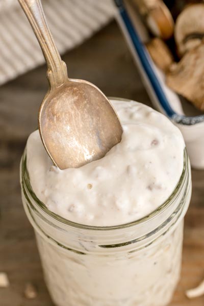 Close-up of a spoon scooping creamy keto cream of mushroom soup to show its thick, condensed texture.