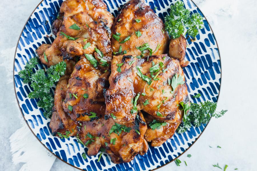 a platter of char grilled huli chicken with chopped parsley on top