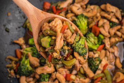 A wood spoon holding a scoop of Chinese stir fry.