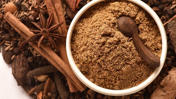 a bowl with garam masala and a bunch of dried spices piled up