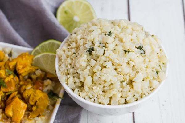 a bowl of cilantro lime cauli rice next to butter chicken