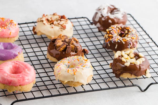 nine donuts with different toppings on a wire rack