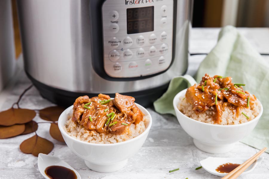 two chinese chicken bowls in front of an instant pot