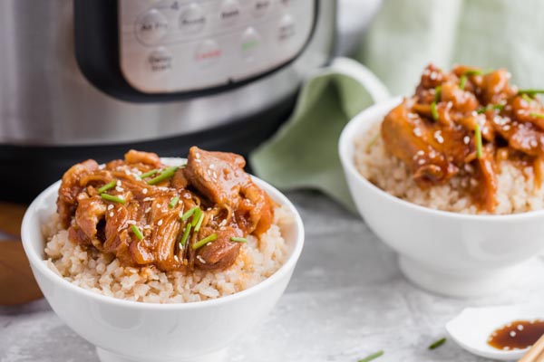 two bowls of keto sesame chicken in front of an instant pot