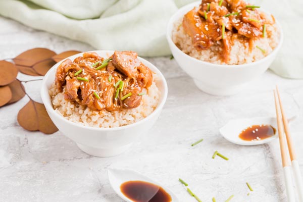 two bowls of sesame chicken with chopsticks near