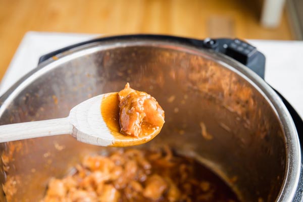 a wood spoon full of sesame chicken sauce