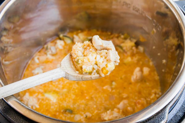 a wooden spoonful holding a biteful of chicken and cauliflower rice