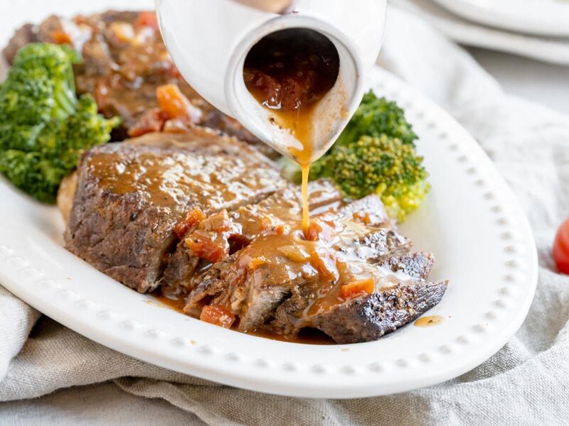 pouring sauce on top of steak on a platter
