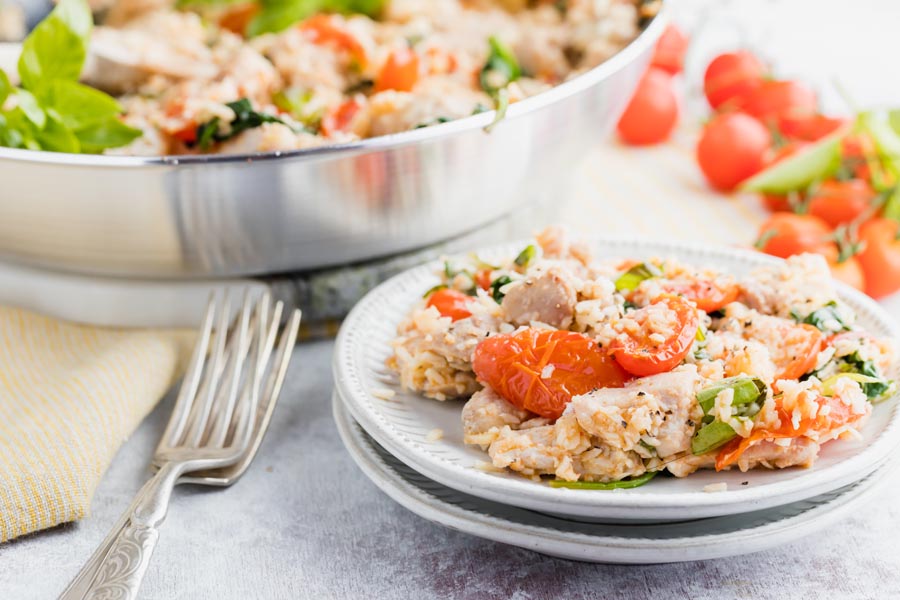 two dinner plates stacked with chicken casserole on it next to forks