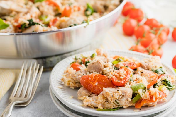 a plate with chicken and rice casserole on it next to the skillet