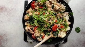 combining rice and chicken with vegetables in a skillet