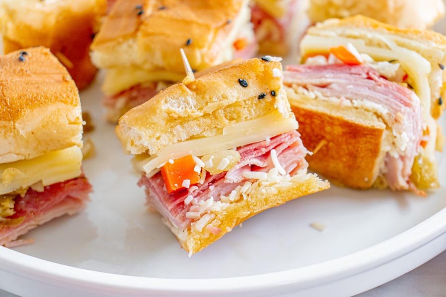 Mini sandwiches on a plate filled with cheese, meat and giardiniera mix.