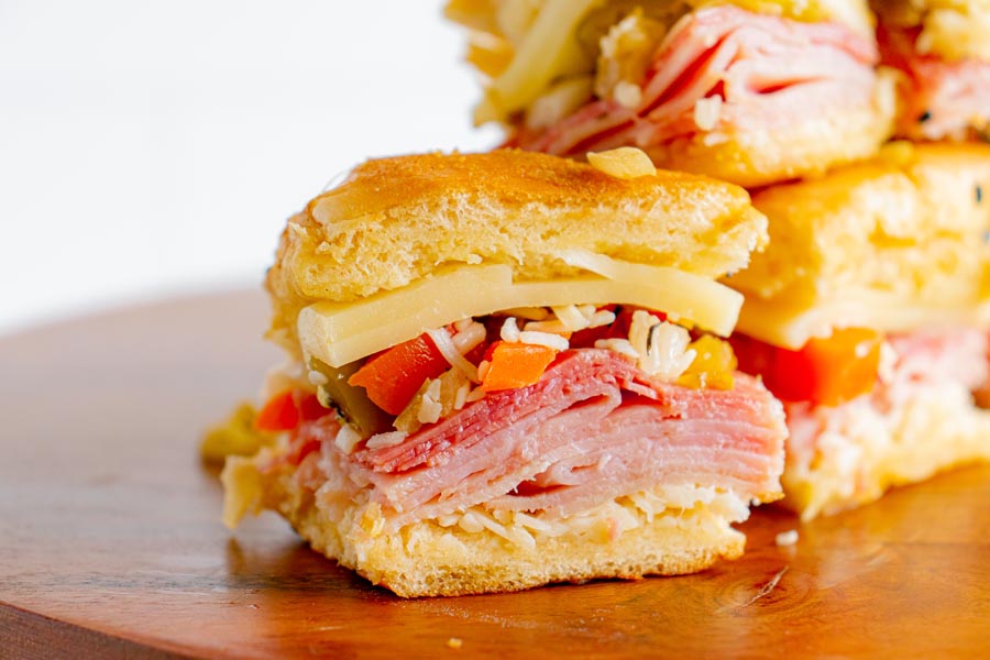 Close up of an mini low carb Italian sandwich filled with shredded cheese, meats and olive spread.