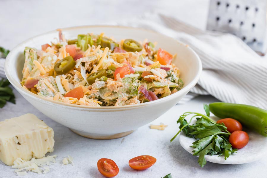 jalapeno based salad with cheese and tomatoes in a bowl next to fresh veggies