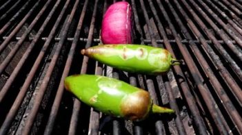 two jalapenos and a red onion cooking on a grill