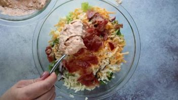 mixing dressing onto a bacon topped salad