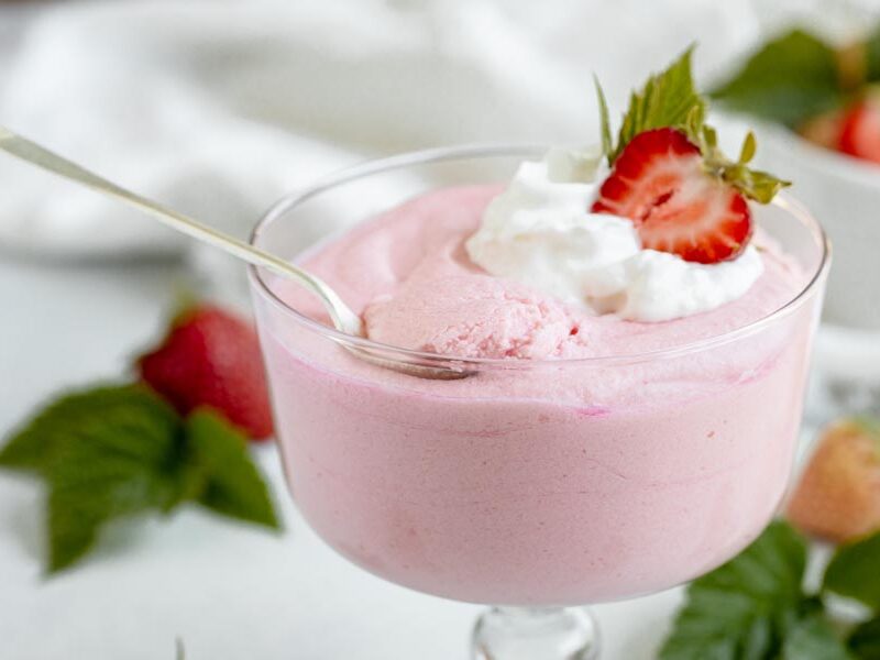 a spoon sitting on top of a trifle dish with strawberry jello whip inside