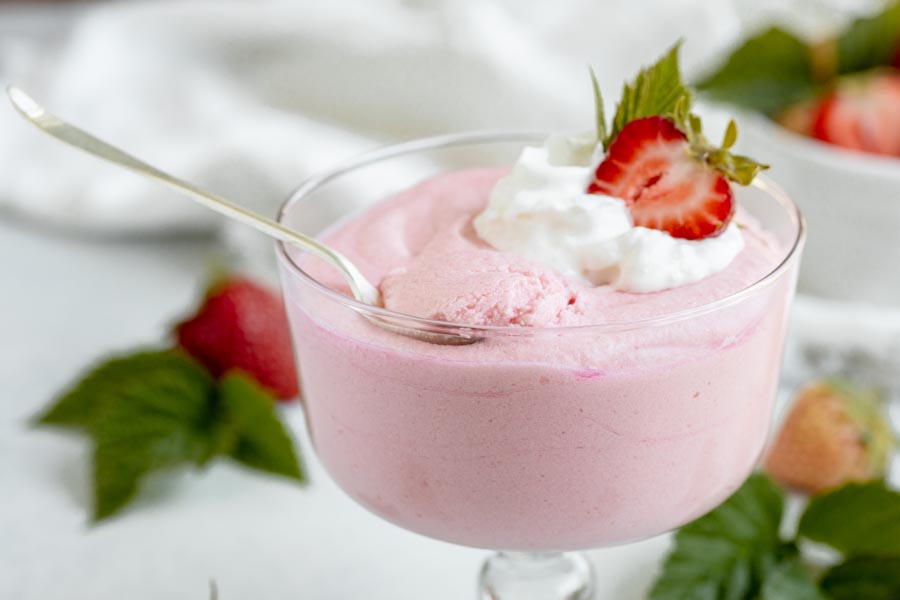 a spoon sitting on top of a trifle dish with strawberry jello whip inside