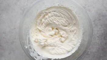 a bowl of whipped cream beaten with stiff peak ribbons on top