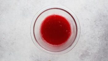 a clear bowl with red liquid gelatin inside