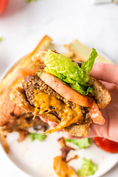 A hand holding a half a burger with melted cheese stuffed inside the patty.