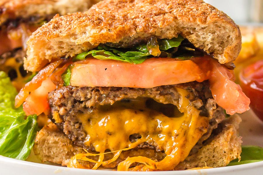 A close look inside a cheese stuffed burger with lettuce, tomato and bacon.