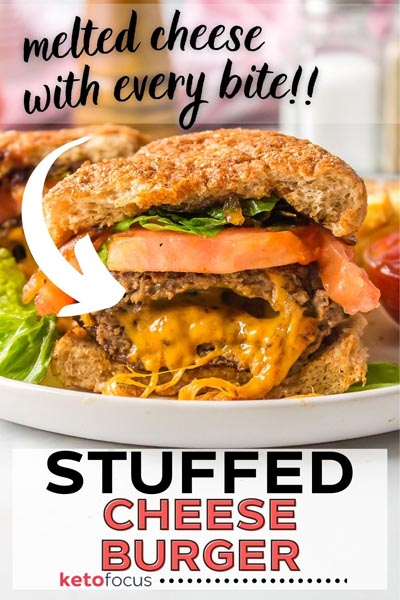 A stuffed cheeseburger filled with melted cheese on a plate with lettuce, tomato and a bun.