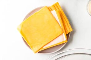 Slices of cheddar cheese on a plate.