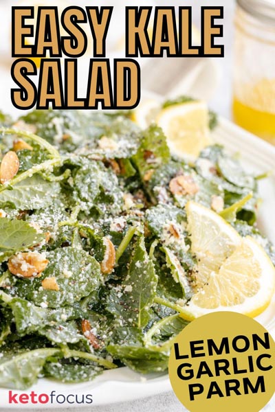 Close up of kale salad tossed with grated parmesan cheese and nut with lemon slices placed on top.