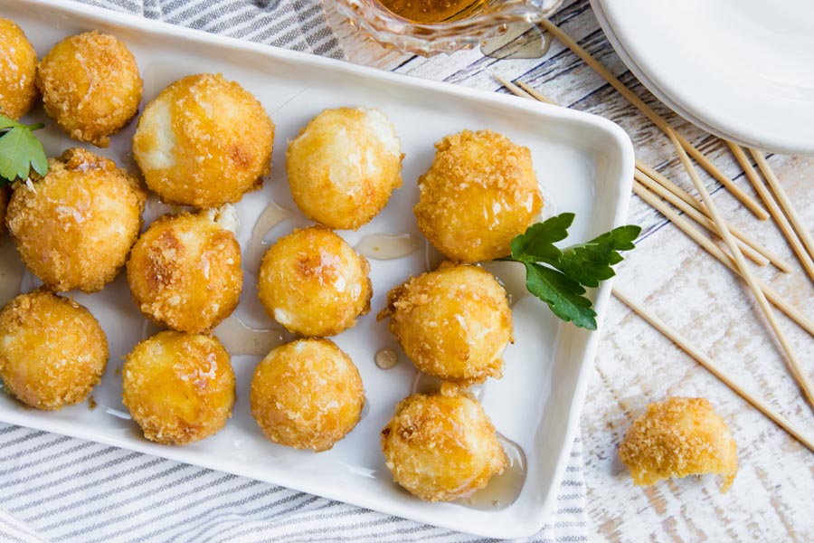 rows of cheese balls appetizer on a plate with small plates nearby