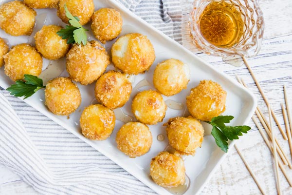 crispy cheese balls with caramel syrup on top next to toothpicks