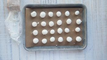 24 goat cheese balls on a parchment lined tray