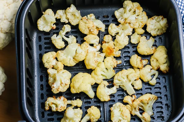 crispy chunks of fried cauliflower in an air fryer basket