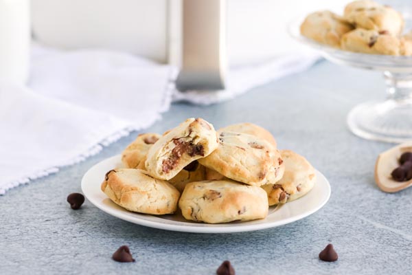 a plate of chocolate chip cookies with chips scattered around and an air fryer behind