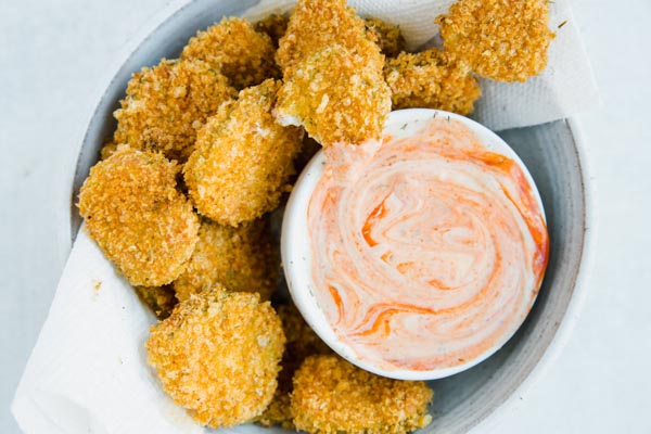 crispy air fried pickle chips in a bowl with spicy ranch dip