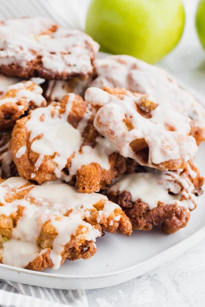 A pile of keto apple fritters topped with a creamy glaze.