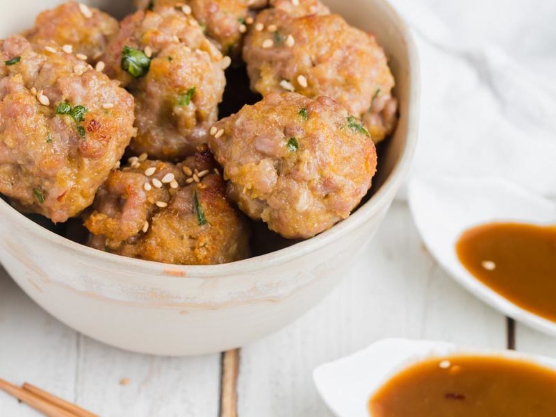 juicy low-carb meatballs with sesame and ginger next to a dish of sauce