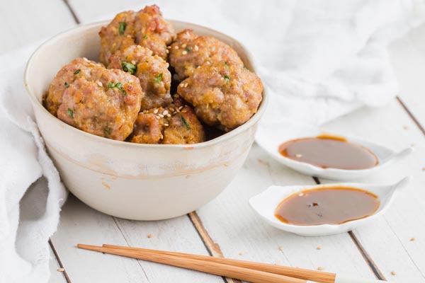 juicy keto asian meatballs in the bowl next to chopsticks