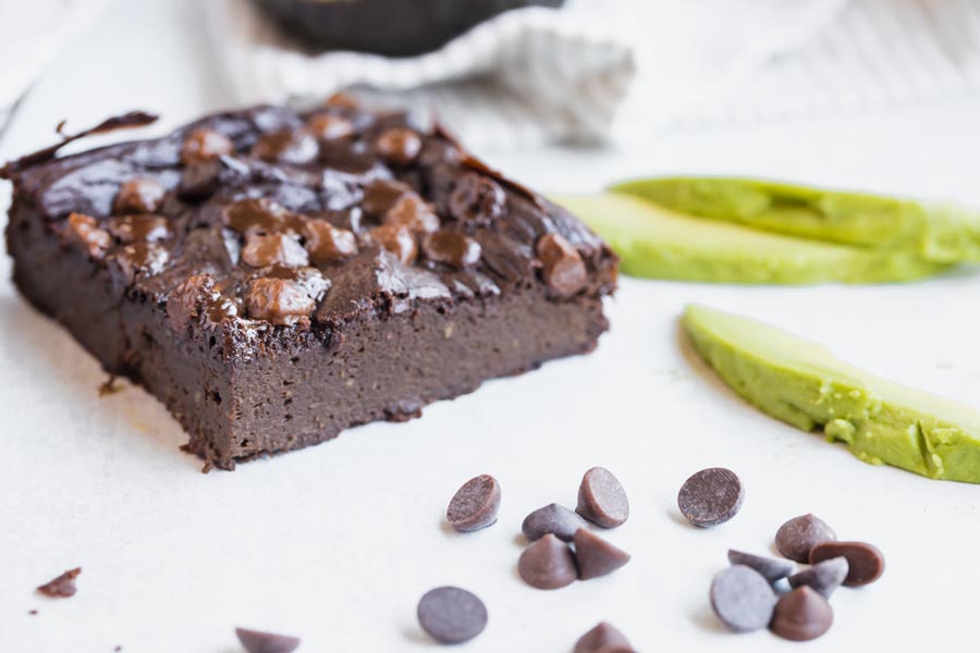 close up of avocado brownies with a couple slices of avocado