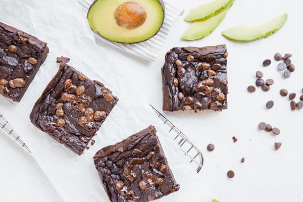 avocado brownies on a white counter arranged near a wire rack and avocado slices around
