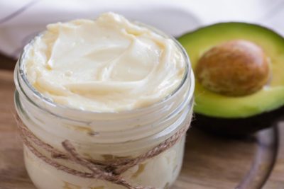 keto avocado oil based mayonnaise in a mason jar with a half an avocado in the background