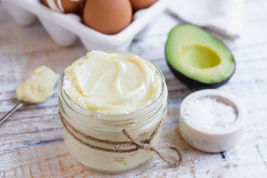 eggs in the background and an halved avocado with a container of avo mayo