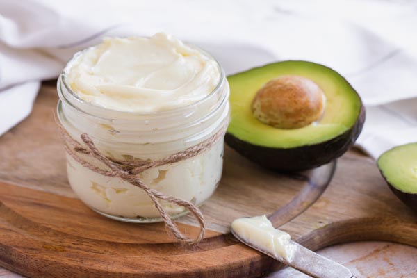 creamy mayo in a mason jar next to an avocado with a butter knife