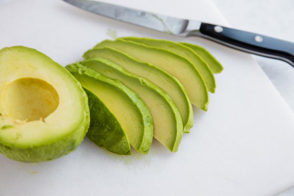 ripe avocado sliced on a cutting board
