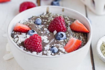 thick raspberries and blueberries along with coconut and seeds on top a smoothie bowl
