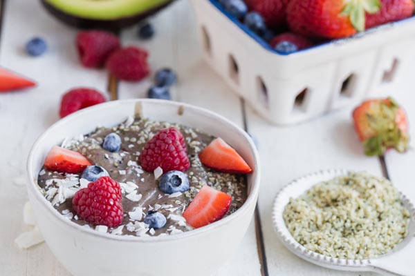 thick smoothie bowl with strawberries and raspberries and a bowl of hemp seeds