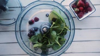 spinach, avocado and berries in a food processor bowl