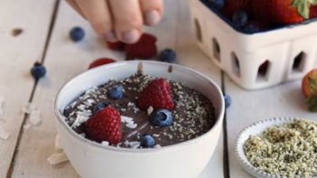 sprinkling coconut and hemp seeds on a smoothie bowl