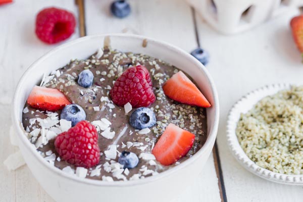 a purple smoothie bowl topped with berries and coconut shreds