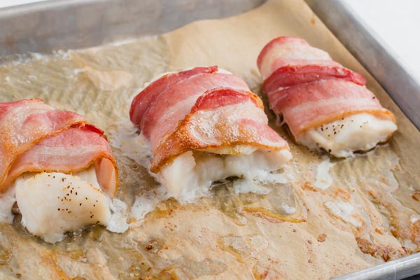 three bacon wrapped fish fillets on a tray